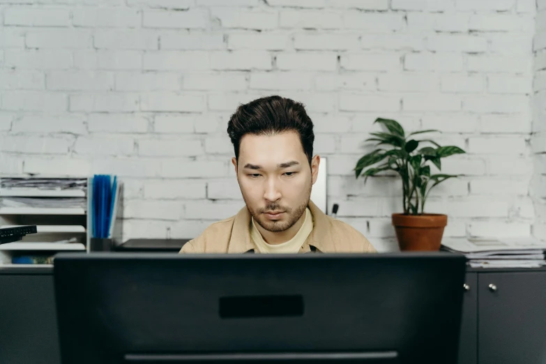 a man sitting at a desk in front of a computer, trending on pexels, asian descent, lachlan bailey, no - text no - logo, brown