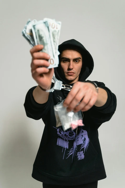 a man in a hoodie holding a bunch of money, an album cover, pexels contest winner, holding ego weapons, diego fernandez, he is wearing a black t-shirt, drugs