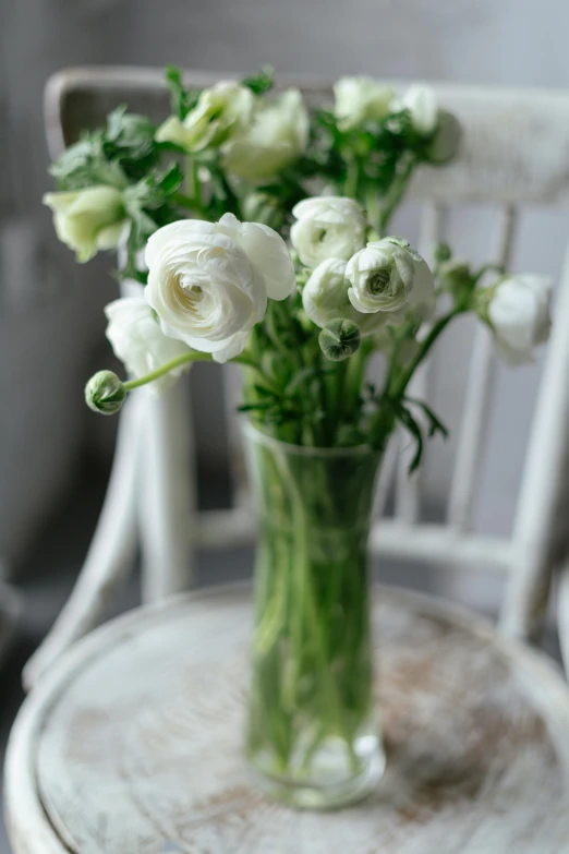 a vase filled with white flowers sitting on top of a wooden table, pale greens and whites, full product shot, clear curvy details, buttercups