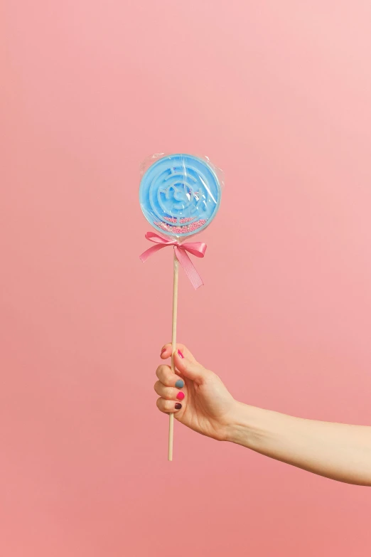 a woman holding a blue and pink lollipop, instagram post, without text, candy decorations, twirls