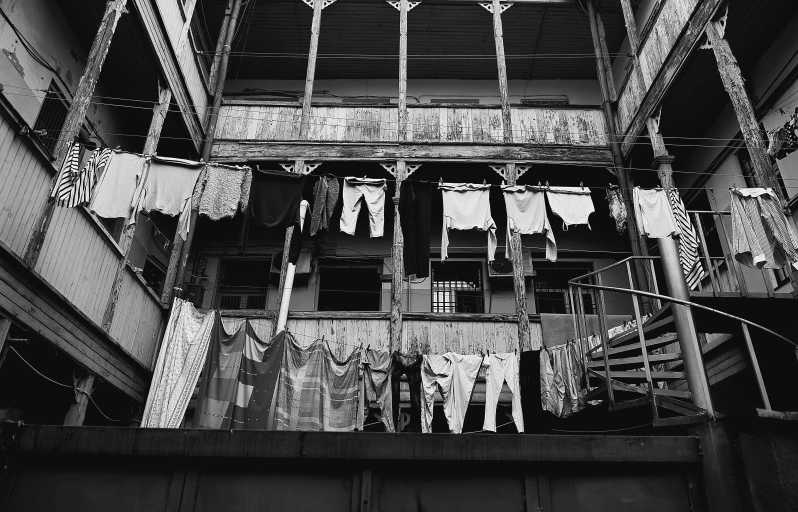 a black and white photo of a building with clothes hanging out to dry, in sao paulo, kowloon walled city style, nepali architecture buildings, interior of a small