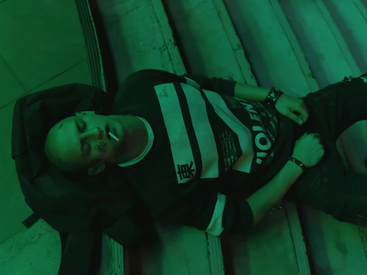 a man that is laying down on some stairs, inspired by Liam Wong, happening, wearing green, at a rave, vin diesel with a tummy, official music video