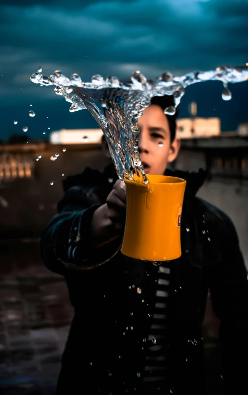 a man holding a yellow cup with water coming out of it, by irakli nadar, pexels contest winner, hyperrealism, water tornado in the city, teenage boy, digital photo, instagram post