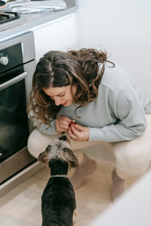 a woman kneeling down petting a dog in a kitchen, by Nicolette Macnamara, pexels contest winner, gif, manuka, crisp detail, profile image