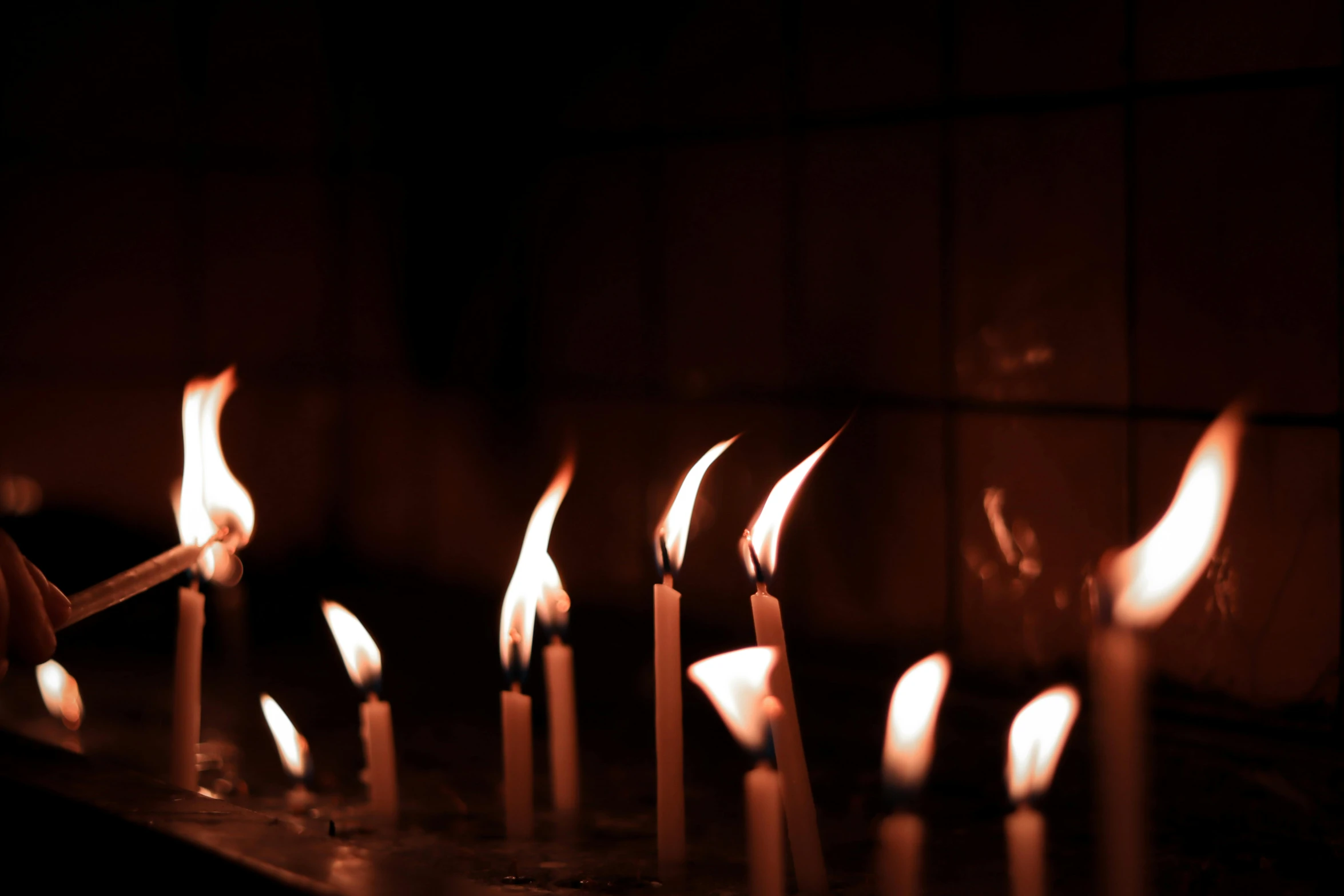 a row of lit candles in a dark room, an album cover, inspired by Elsa Bleda, pexels, wall torches, ignant, religious, happy birthday