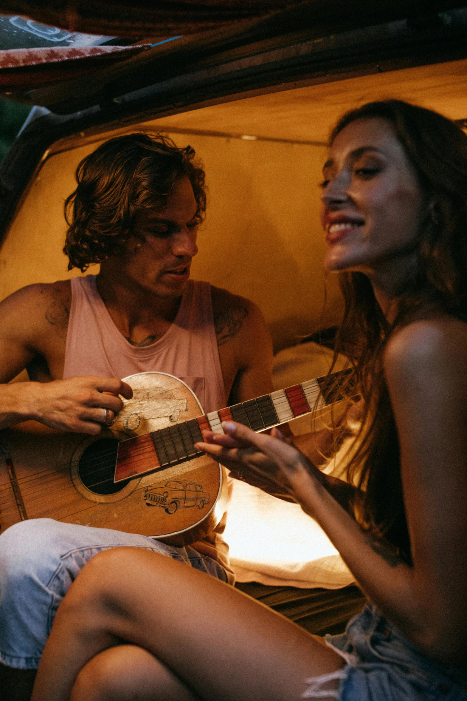 a man playing a guitar next to a woman, profile image, glamping, te pae, frank dillane