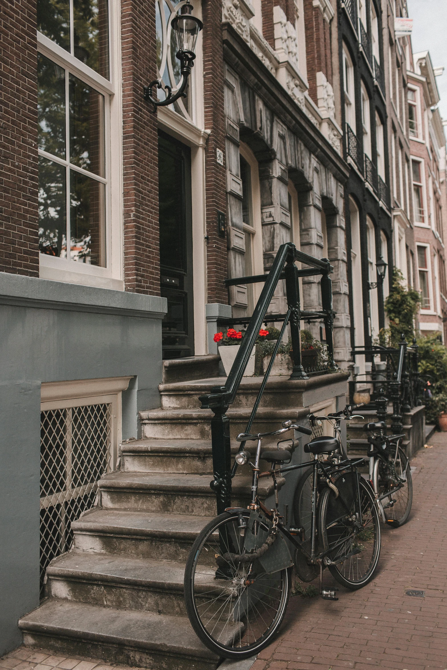 a couple of bikes parked next to a building, dutch tilt, stairway, beautiful surroundings, quiet street