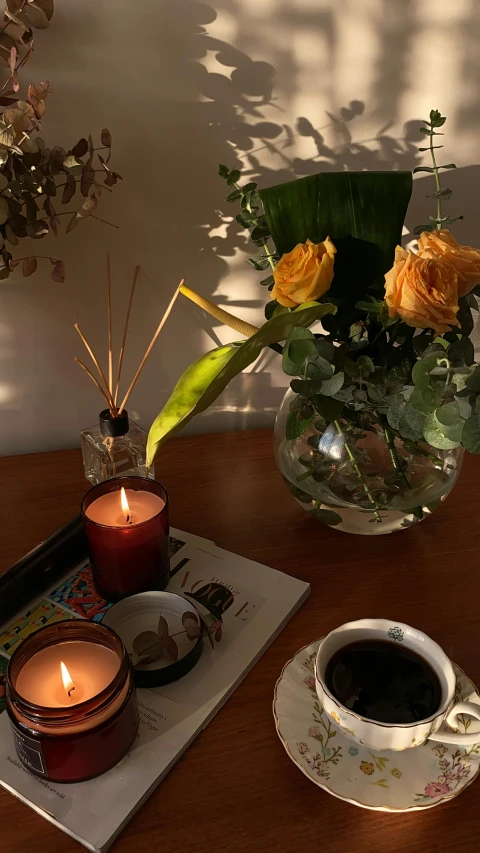 a cup of coffee sitting on top of a wooden table, lamps and flowers, dark lit candles, full product shot, cosy vibes