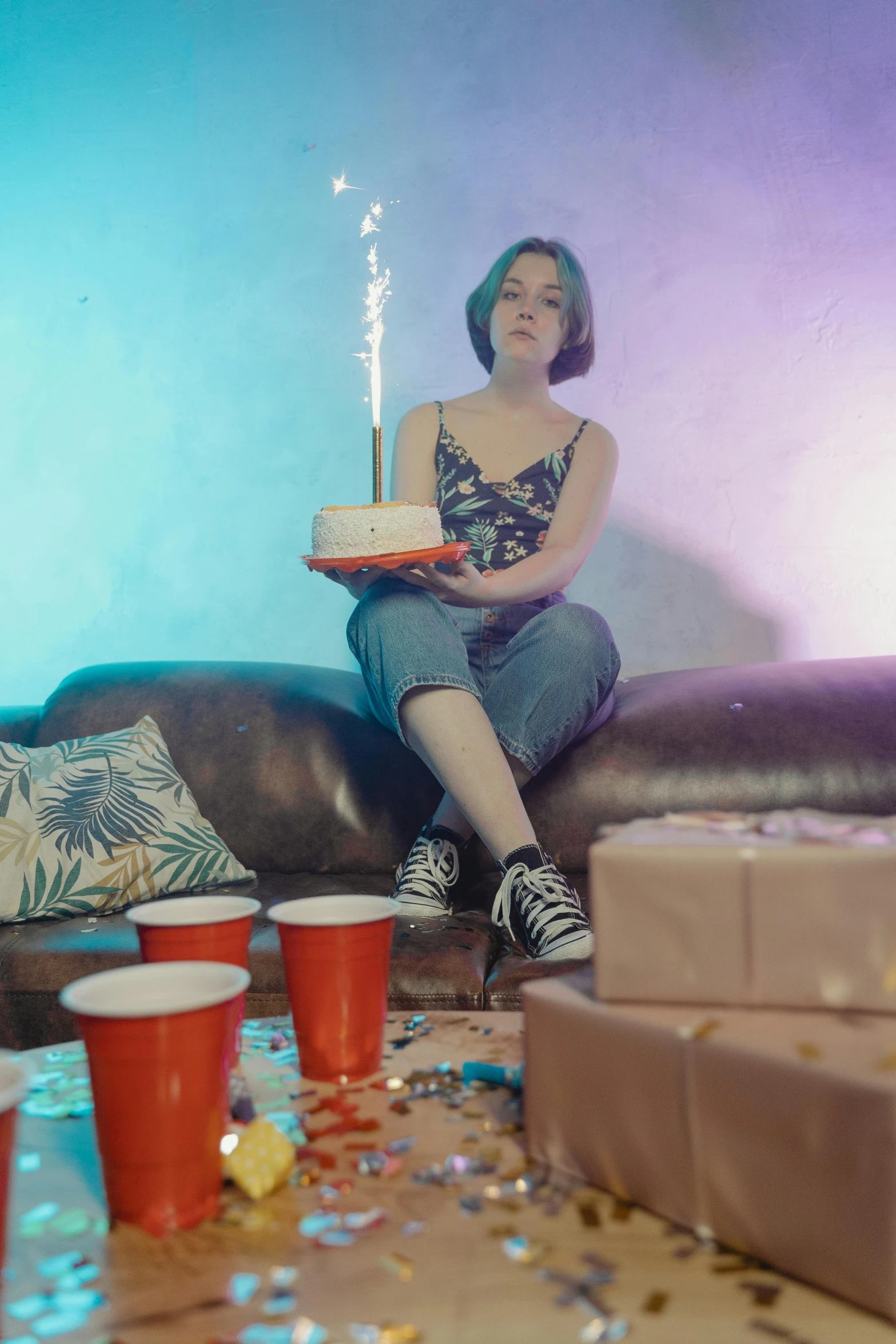 a woman sitting on a couch holding a birthday cake, inspired by Elsa Bleda, pexels contest winner, still from a music video, pyrotechnics, maisie williams, ( ( theatrical ) )