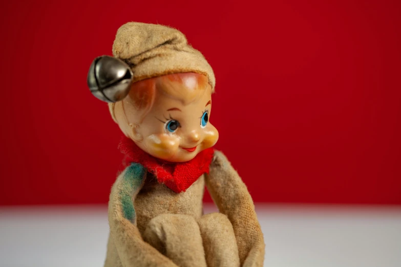 a small toy sitting on top of a table, an album cover, flickr, folk art, portrait of an elf, 15081959 21121991 01012000 4k, red cap, vintage aesthetic