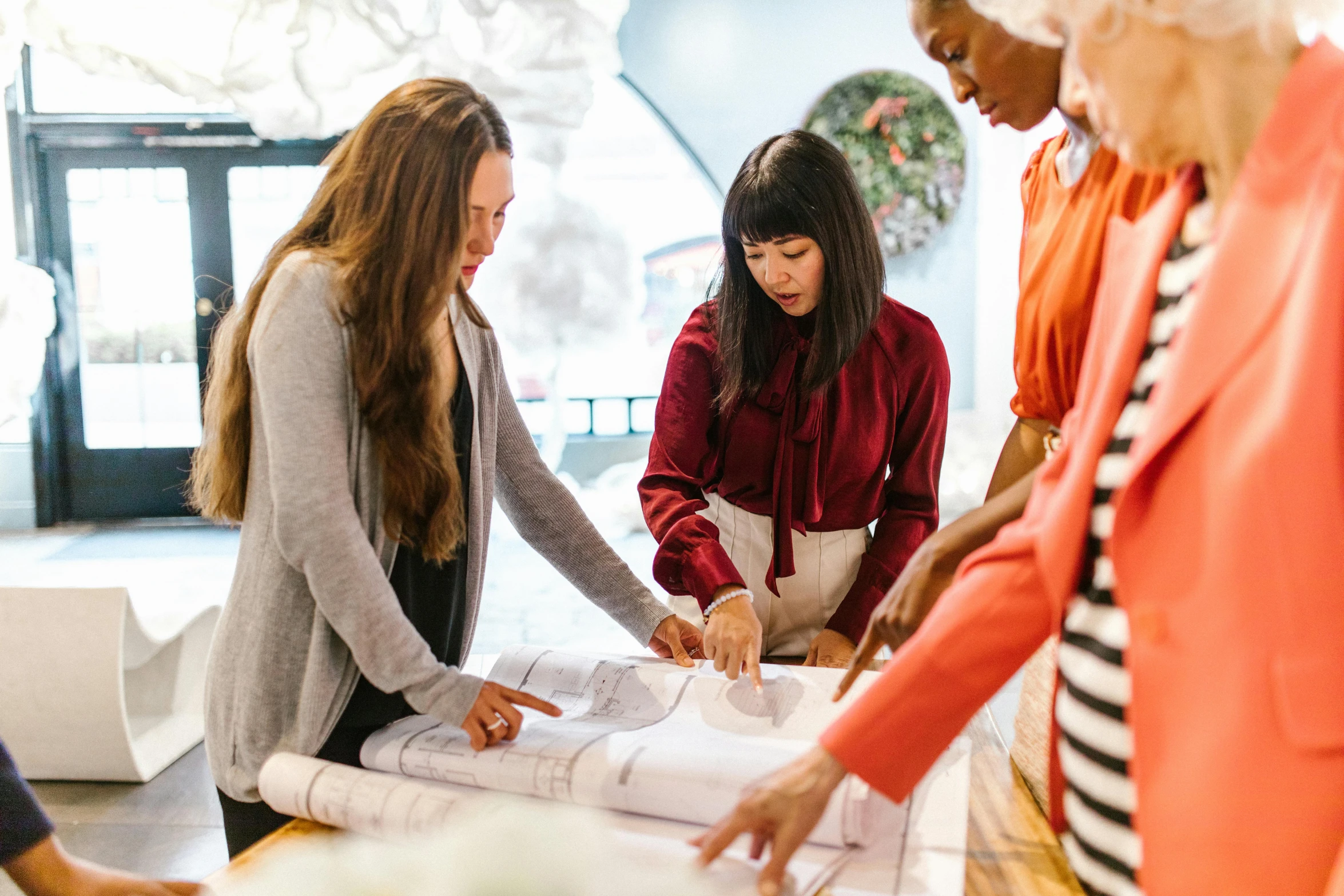 a group of women standing around a table, trending on unsplash, architectural plans, costume design made with love, profile image, centered design