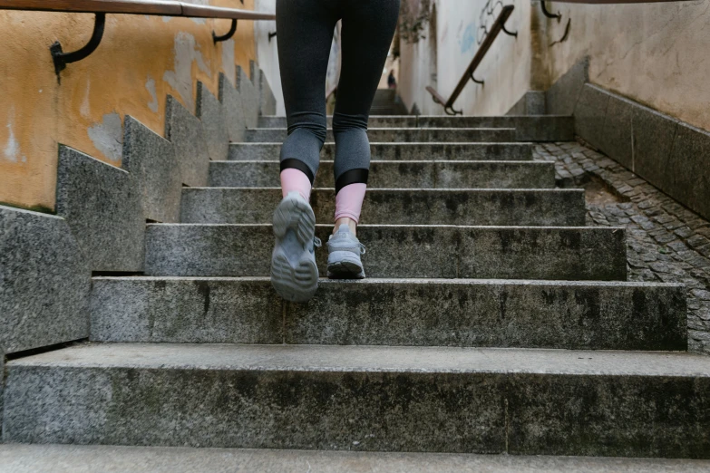 a woman walking up a flight of stairs, pexels contest winner, happening, athletic muscle tone, scabs, gray concrete, wearing fitness gear