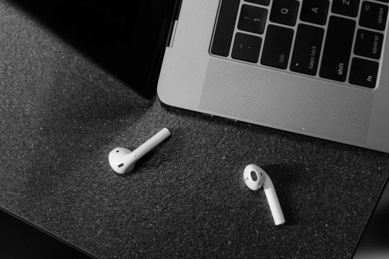 an apple airpods sitting on top of a desk next to a laptop, a black and white photo, by Adam Rex, happening, on a flat color black background, instagram post, 1 2 9 7, seamless