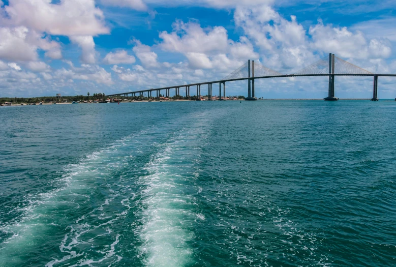 a view of a bridge from the back of a boat, by Felipe Seade, pexels contest winner, the emerald coast, skybridges, with full descriptions, thumbnail