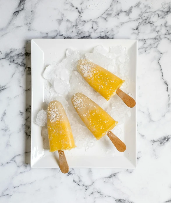 three pops sitting on top of a white plate, inspired by Jacopo Bellini, unsplash, ice sunflowers, froz, shades of gold display naturally, vanilla