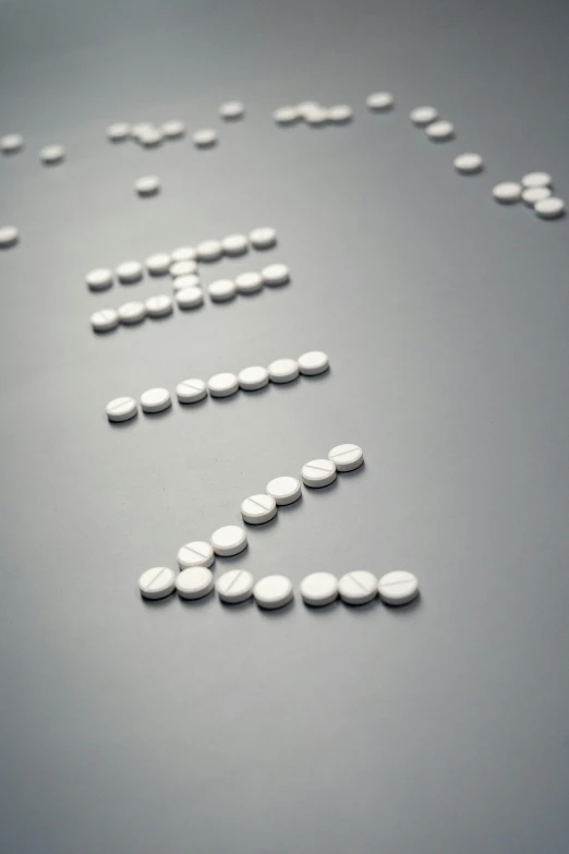 a group of pills sitting on top of a table, inspired by Cerith Wyn Evans, ascii art, dna strands, close up, on a gray background, digital image