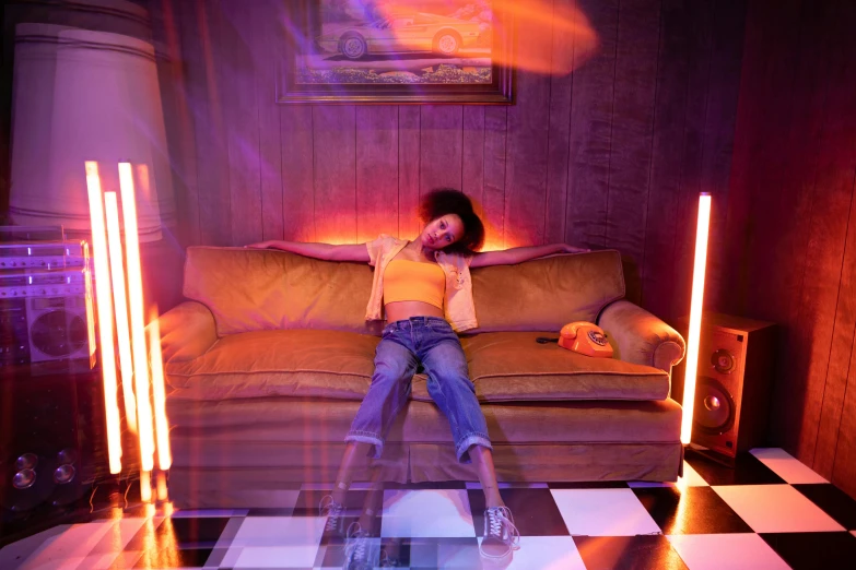 a woman sitting on top of a couch in a living room, inspired by David LaChapelle, trending on pexels, photorealism, purple and yellow lighting, volumetric neon lighting, ashteroth, teenager hangout spot