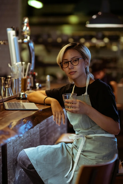 a woman sitting at a bar with a drink, a portrait, trending on unsplash, renaissance, white waist apron and undershirt, asian male, androgynous person, with square glasses