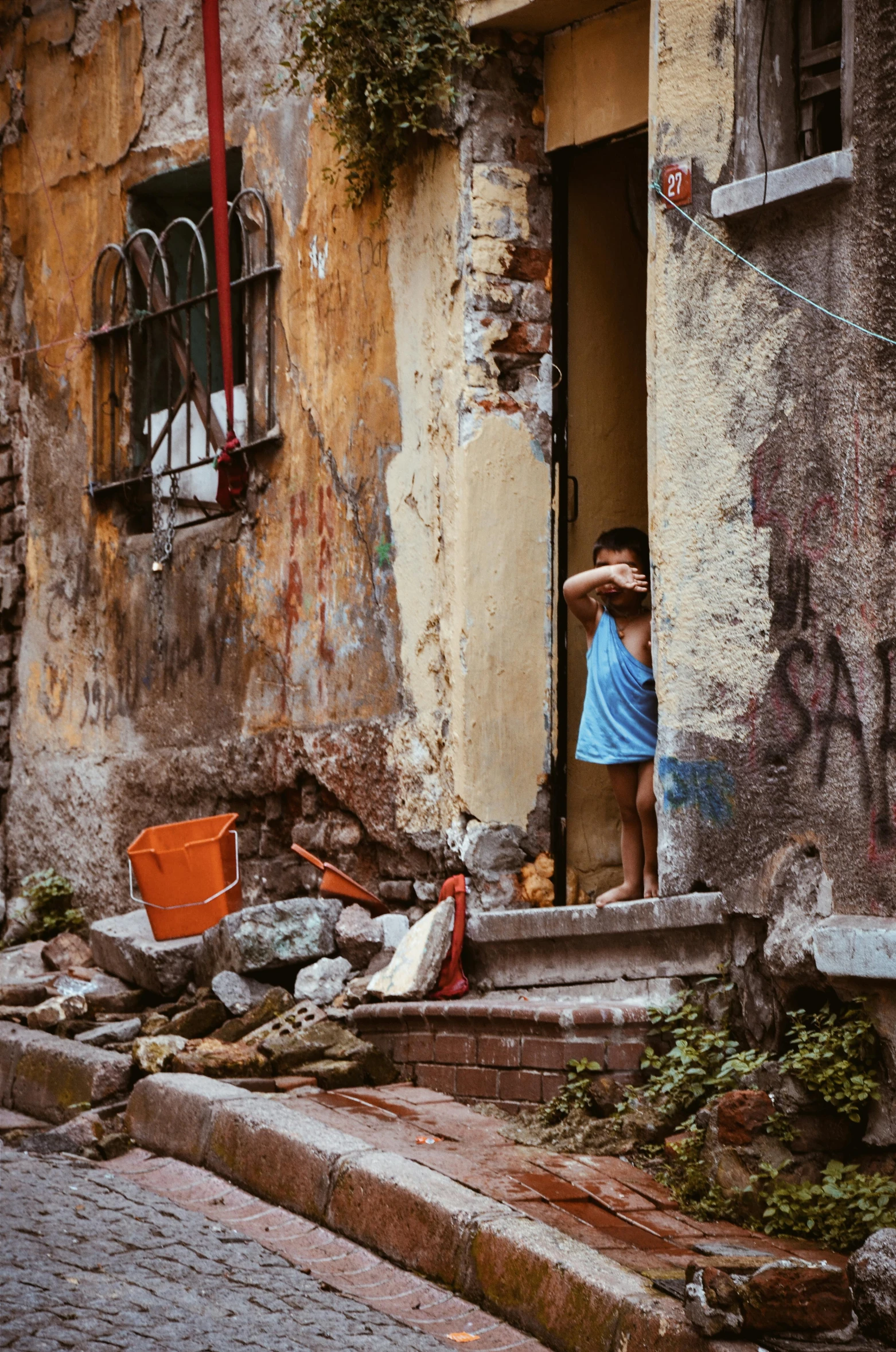 a man that is standing in the doorway of a building, inspired by Steve McCurry, pexels contest winner, street art, rubble, little kid, spying, fintan magee