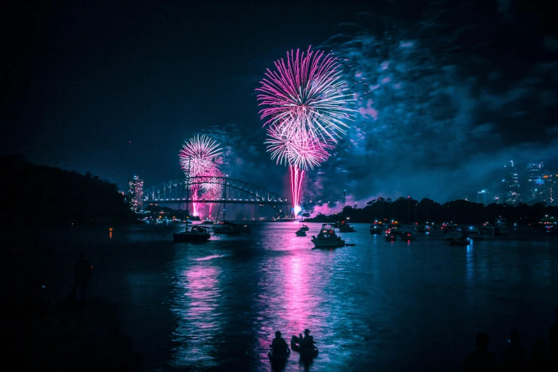 fireworks in the sky over a body of water, by Niko Henrichon, pexels contest winner, hurufiyya, sydney mortimer laurence, cyan and magenta, zac retz, historical photo