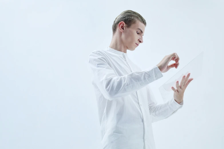 a man in a white shirt holding a piece of paper, an album cover, unsplash, kinetic art, delicate androgynous prince, cardistry, transparent cloth, side profile shot