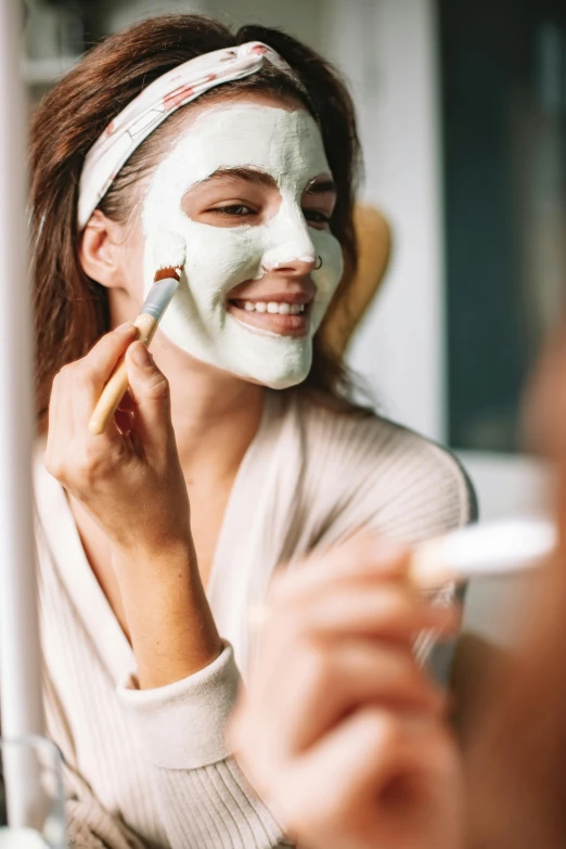 a woman is putting a facial mask on her face, by Nicolette Macnamara, trending on pexels, renaissance, a still of a happy, brunette, a green, covered in