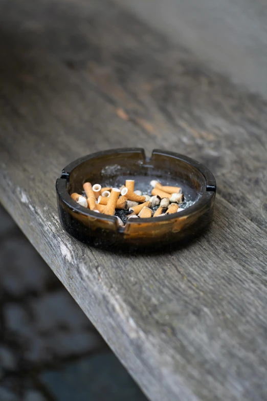 a brown ashtray sitting on top of a wooden table, a still life, unsplash, paul barson, cavities, woodfired, black