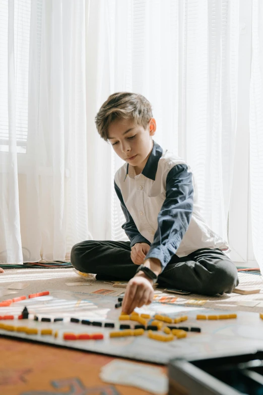 a little boy sitting on the floor playing with a train set, a child's drawing, pexels contest winner, board games on a table, male teenager, serious business, gif