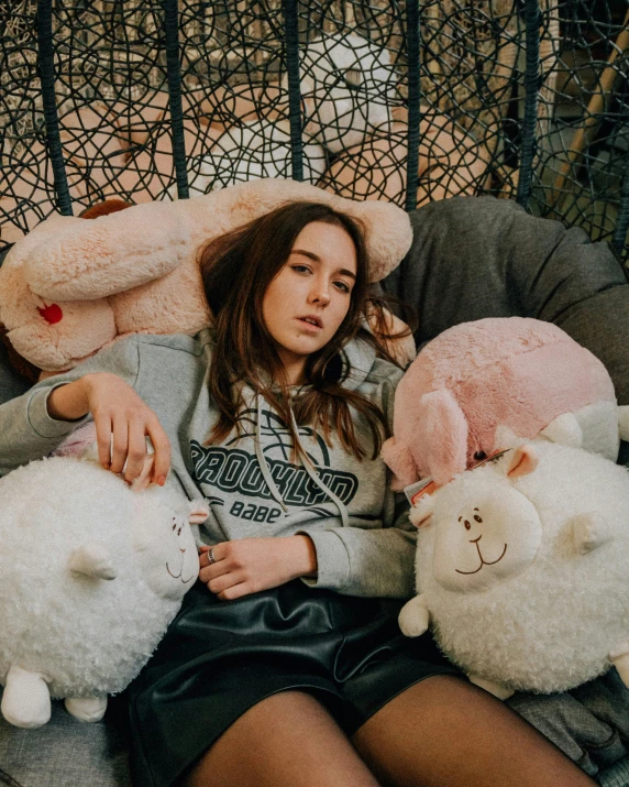 a woman sitting on a couch with stuffed animals, inspired by Elsa Bleda, trending on pexels, portrait sophie mudd, sheep, woman in streetwear, low quality photo