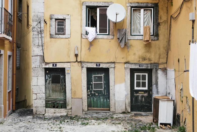 a building with a satellite dish on top of it, pexels contest winner, graffiti, portugal, dirty linen robes, 3 doors, tenement buildings