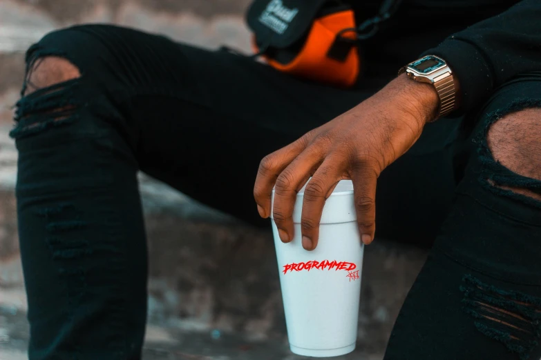 a close up of a person holding a cup of coffee, by Adam Marczyński, trending on pexels, photorealism, chief keef, wearing off - white style, energy drink, sitting down