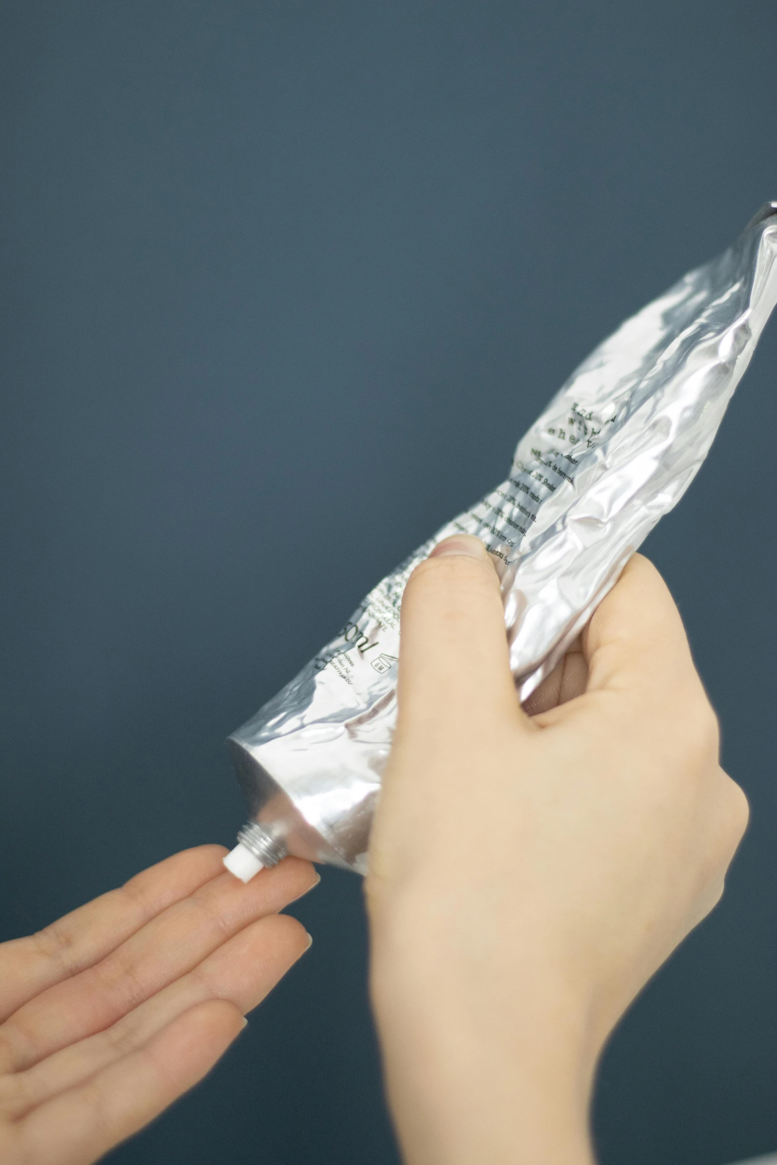 a person holding a piece of foil in their hand, by Jang Seung-eop, unsplash, photorealism, toothpaste refinery, on clear background, iv pole, instructions