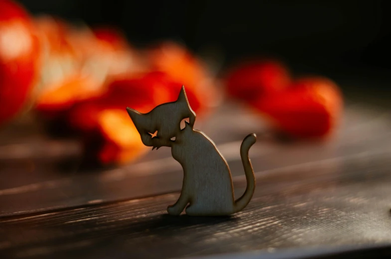 a cat figurine sitting on top of a wooden table, a macro photograph, by Julia Pishtar, unsplash, laser cut, spooky autumnal colours, sassy pose, wooden decoration