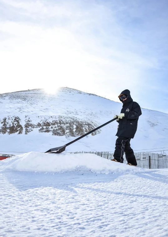 a man that is standing in the snow with a shovel, iceland hills in the background, 2019 trending photo, working hard, covered!