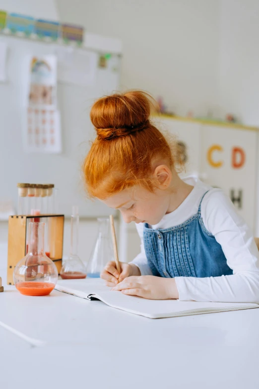 a little girl sitting at a table writing on a piece of paper, pexels contest winner, one is a redhead, with book of science, 15081959 21121991 01012000 4k, panoramic view of girl