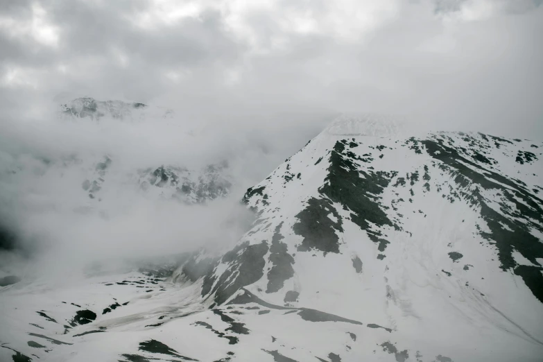 a group of people standing on top of a snow covered mountain, an album cover, pexels contest winner, hurufiyya, low clouds after rain, aerial footage, overcast gray skies, “ aerial view of a mountain