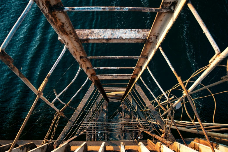 a ladder going up to the top of a boat, an album cover, unsplash, industrial rusty pipes, wide high angle view, sea underneath, high quality photo