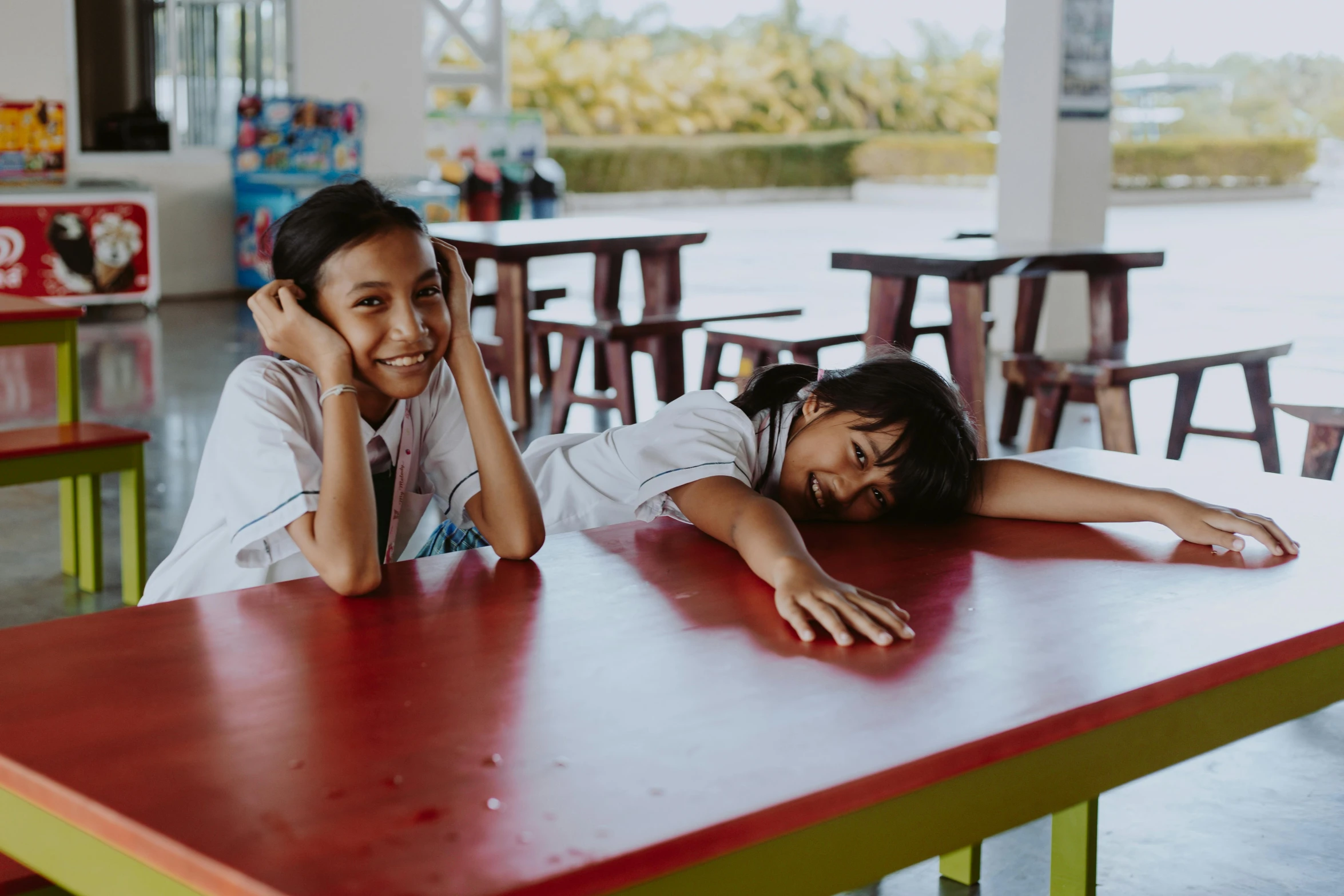 a couple of people that are sitting at a table, girl wearing uniform, happily tired, portrait featured on unsplash, girls resting