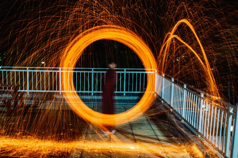 a person standing in front of a fire ring, by Sebastian Spreng, pexels contest winner, process art, spinning whirlwind, orange halo, person in foreground, intricate illuminated lines