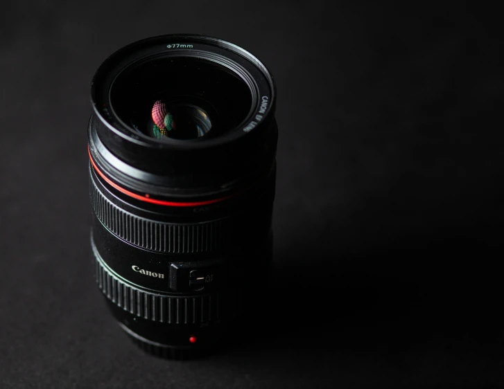 a close up of a camera lens on a table, on a black background, taken with canon 5d mk4, f/3.2, 50mm photo