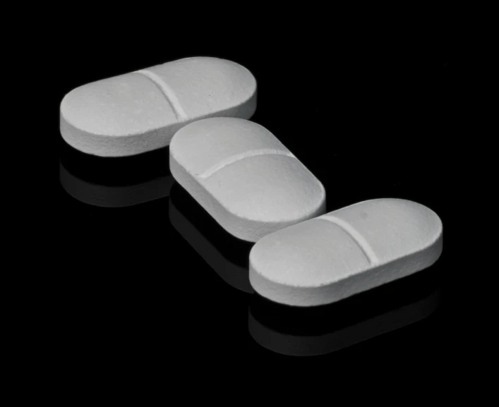 three white pills sitting on top of a black surface, by Maurycy Gottlieb, pixabay, bauhaus, soft pads, neoprene, made of all white ceramic tiles, smooth oval head