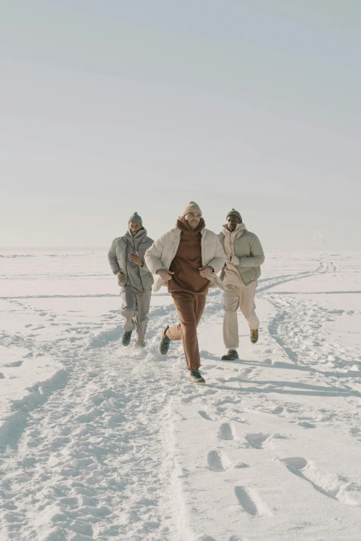 a group of people walking across a snow covered field, an album cover, pexels contest winner, brown clothes, wearing a track suit, helsinki, north pole