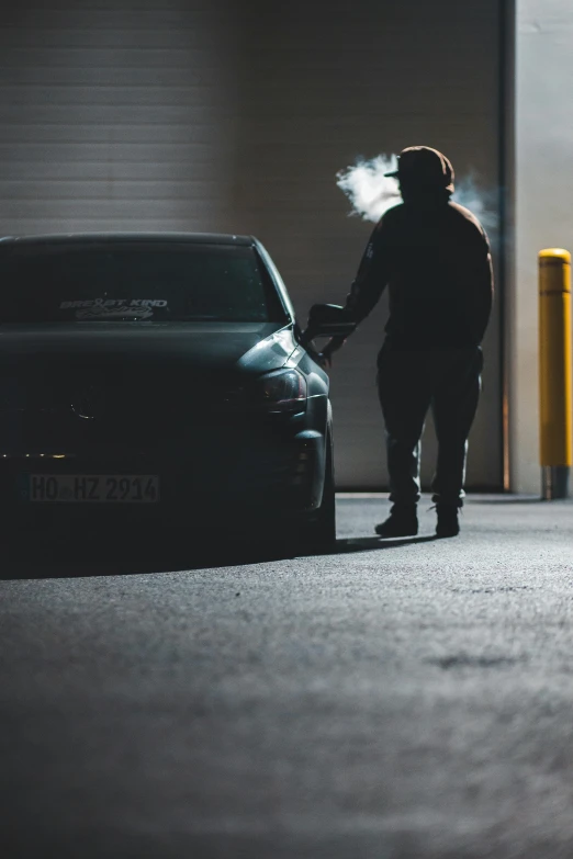 a person standing next to a car in a garage, pexels contest winner, smoking outside, strong silhouette, profile image, instagram picture