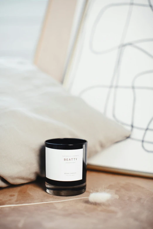 a candle sitting on top of a table next to a pillow, a black and white photo, all black matte product, breathe, in a medium full shot, graphic detail