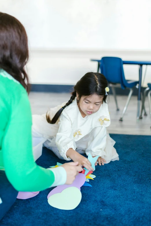 a woman sitting on the floor next to a little girl, inspired by Li Di, danube school, korean, private school, profile image, teaching