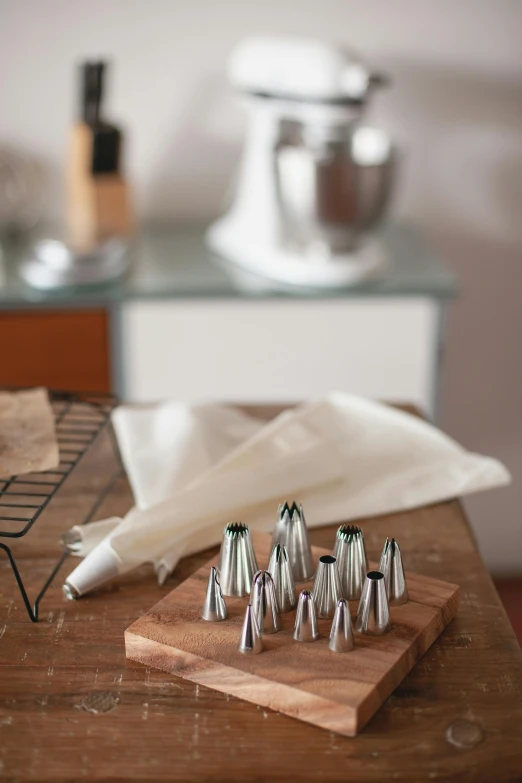 a wooden table topped with a wooden cutting board, piping, spire, baking a cake, made of brushed steel