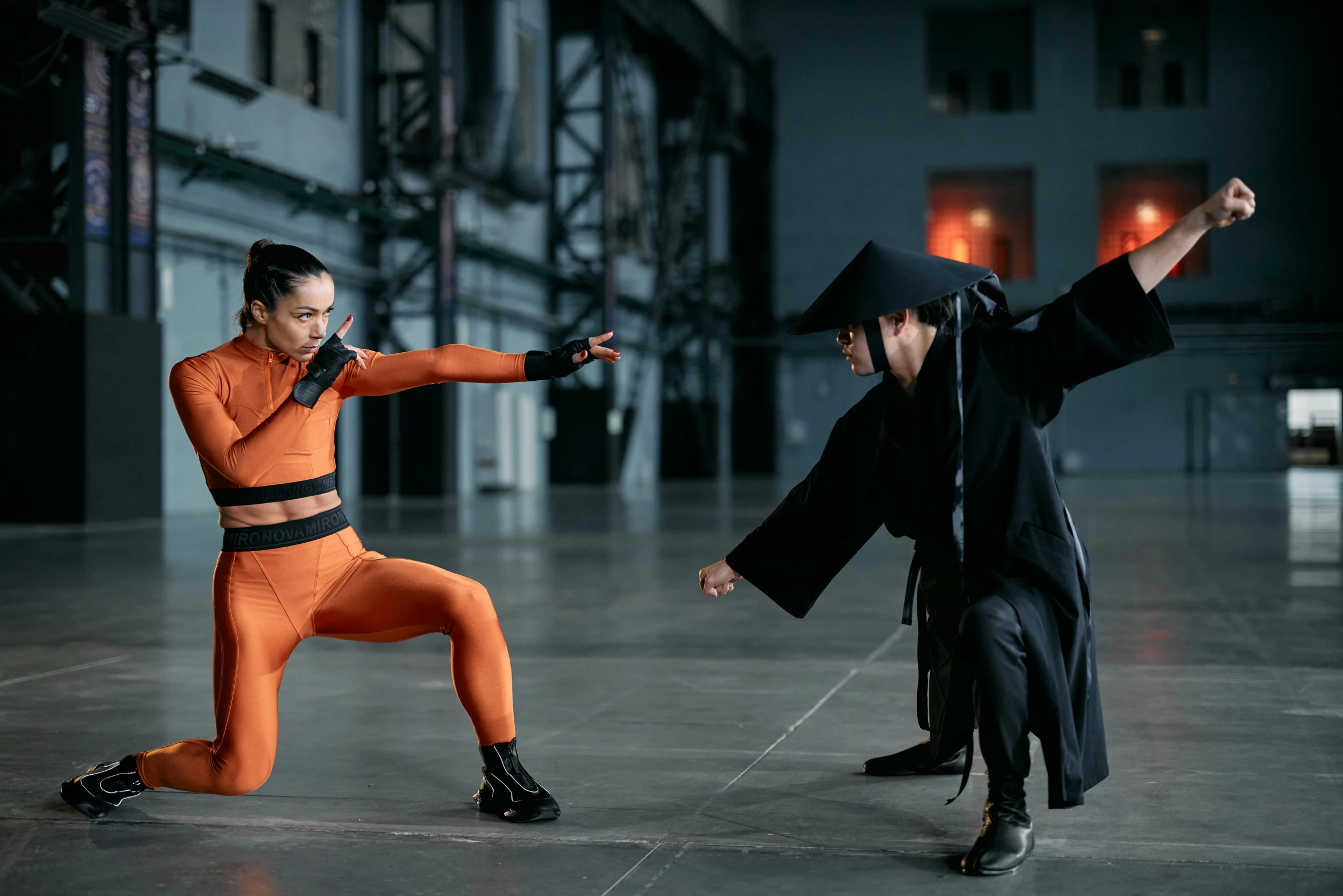 a couple of people standing on top of a cement floor, inspired by Kanō Hōgai, pexels contest winner, antipodeans, in orange clothes) fight, wearing black sith uniform, film still of gal gadot, wearing a tracksuit