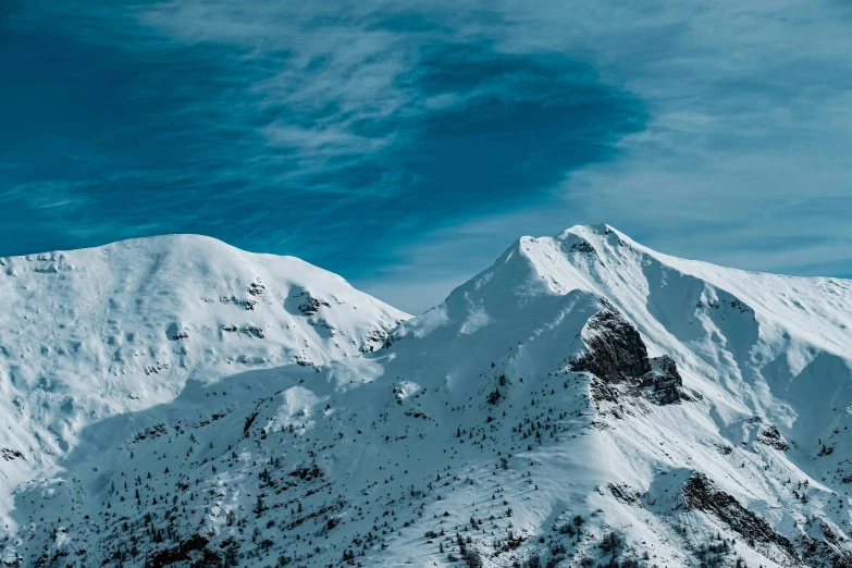 a man riding a snowboard down the side of a snow covered mountain, pexels contest winner, irish mountains background, thumbnail, two mountains in background, cold blue colors