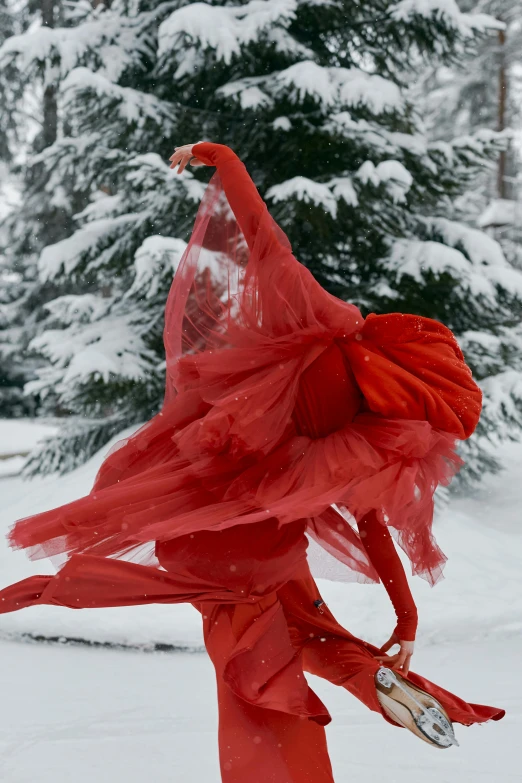 a woman in a red dress is standing in the snow, an album cover, inspired by Scarlett Hooft Graafland, arabesque, swirling red-colored silk fabric, in a snowy forest setting, contemporary dance, dressed in a worn