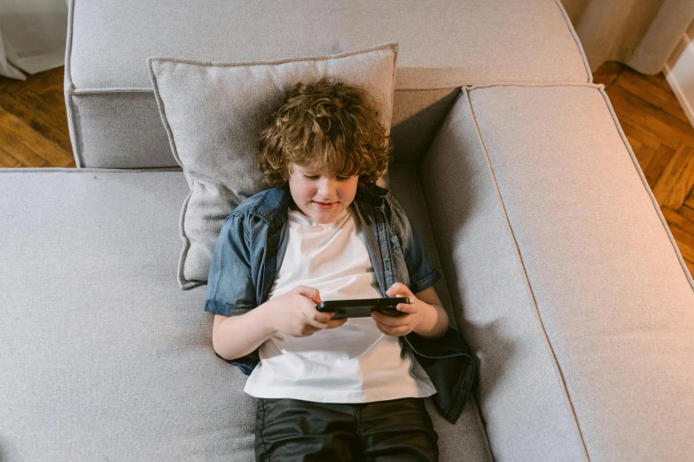 a boy sitting on a couch using a cell phone, pexels, pixel art, tabletop gaming, on a couch, v tuber, young child